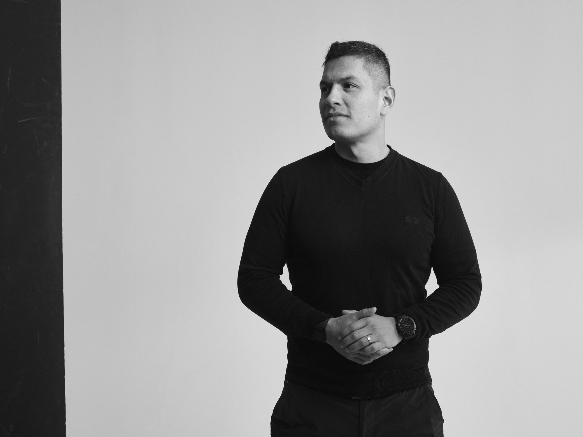 Daniel Laurean standing beside a dark pillar in a studio